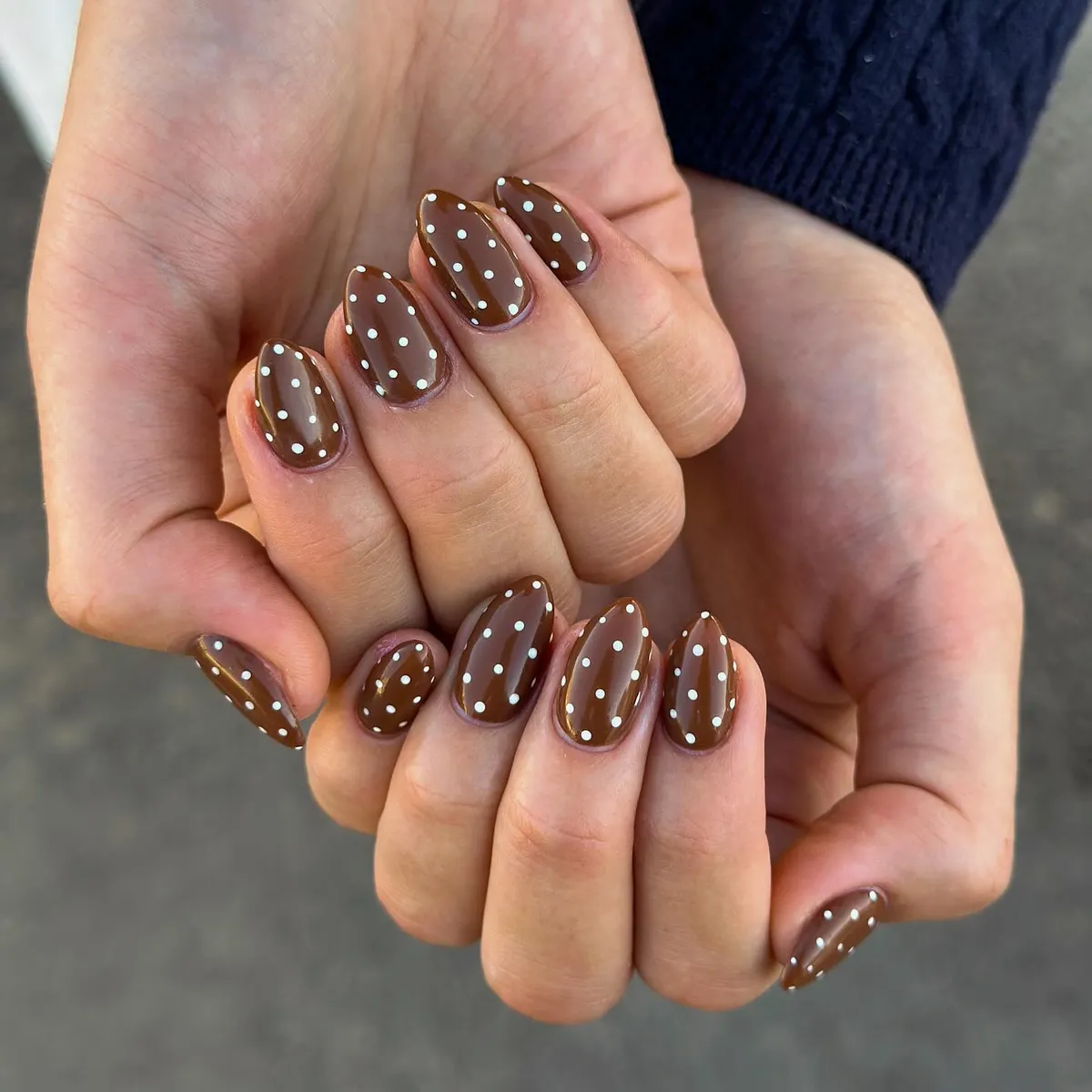 Glossy brown almond nails with white polka dots