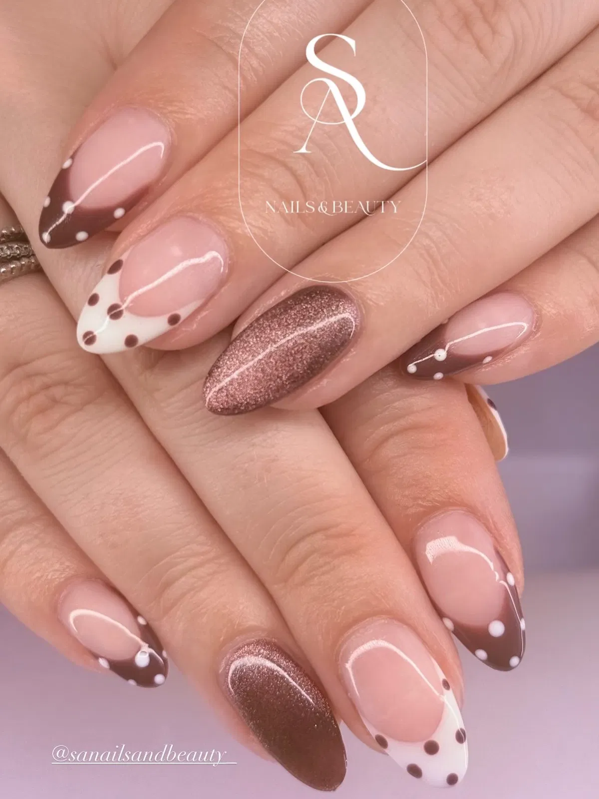 Brown-and-white dotted French tips with rose-gold glitter accents