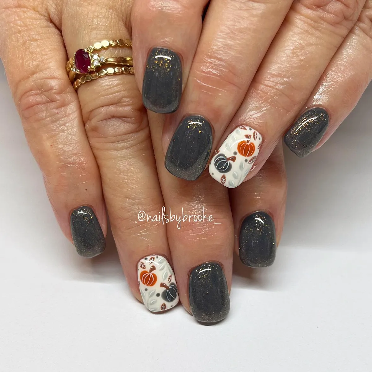 Shimmery charcoal nails with embossed leaves and pumpkin accents