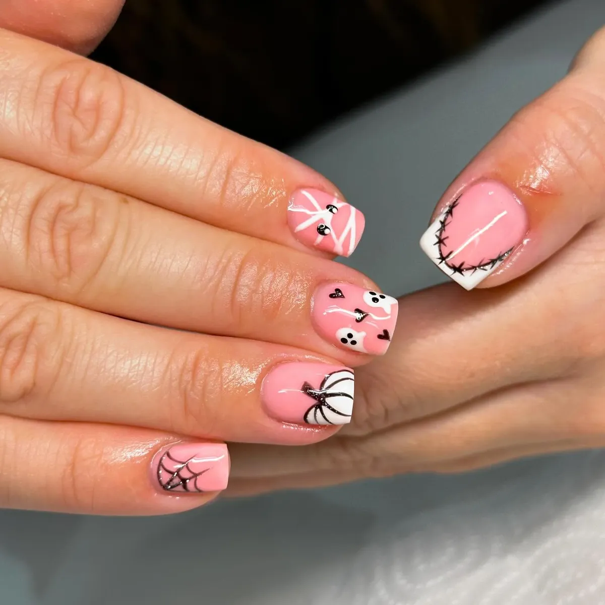 Short pink nails with web, mummy eyes, and stitched tip