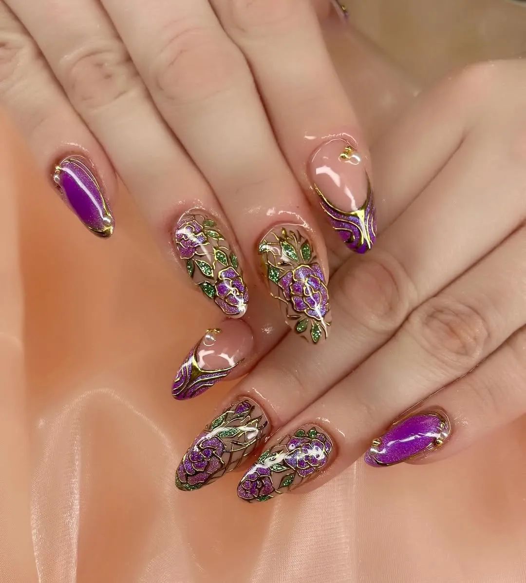 Gold-outlined floral nail art with plum and green glitter