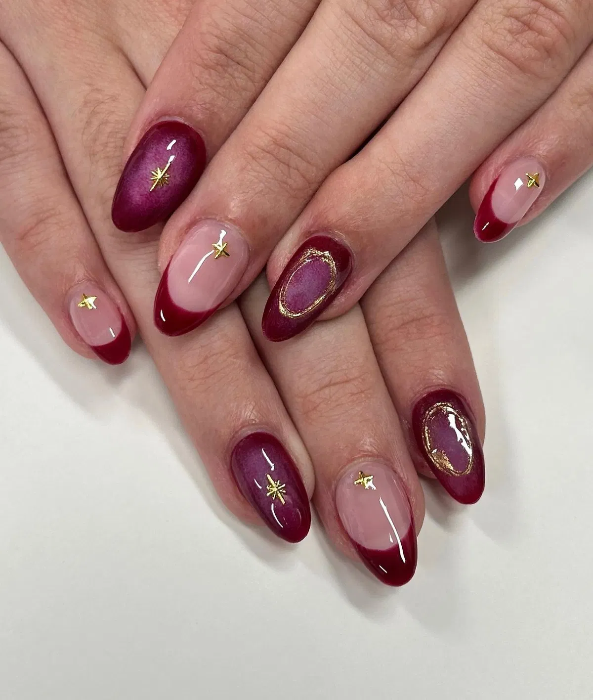 Deep plum-red French tips with gold star accents
