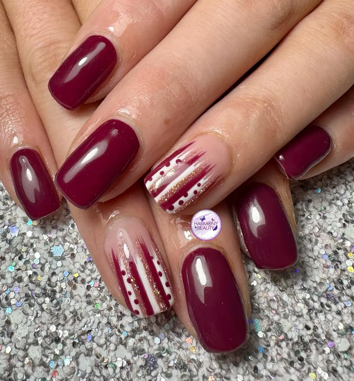 Deep plum with striped nude-and-gold accent nails