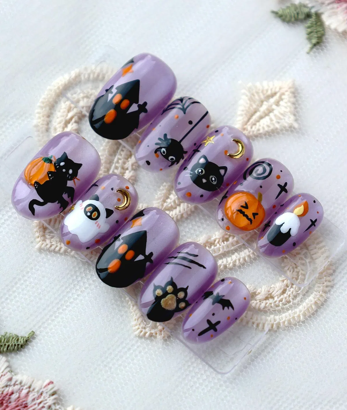 Lavender press-ons with cats, pumpkins, ghost, bats, and gold moon/star accents