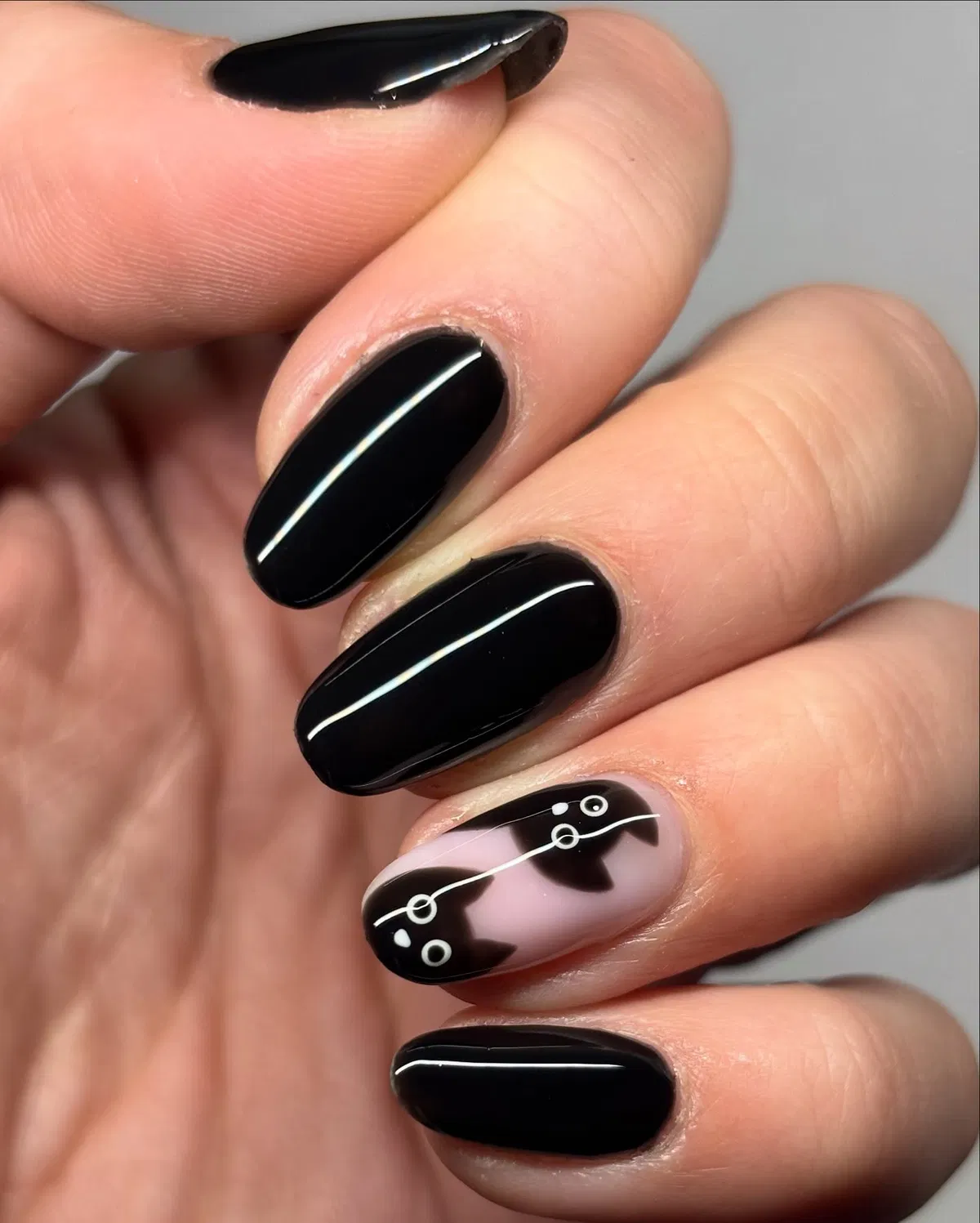 Glossy black nails with a mauve bat accent