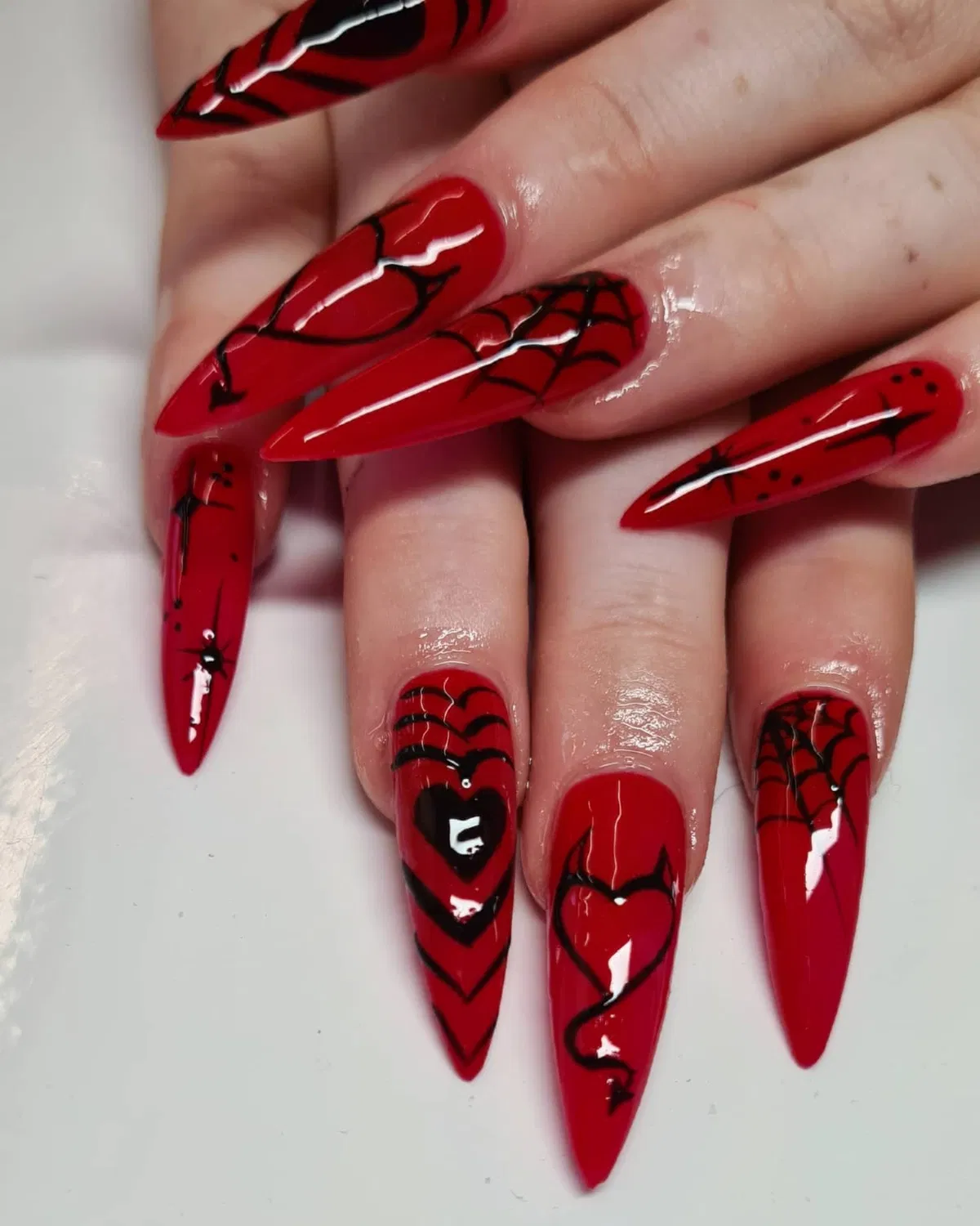 Red stiletto nails with black webs and hearts