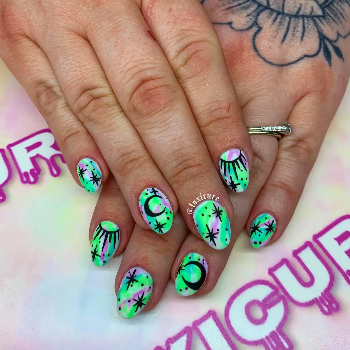 Neon green and purple marbled nails with black moons and stars