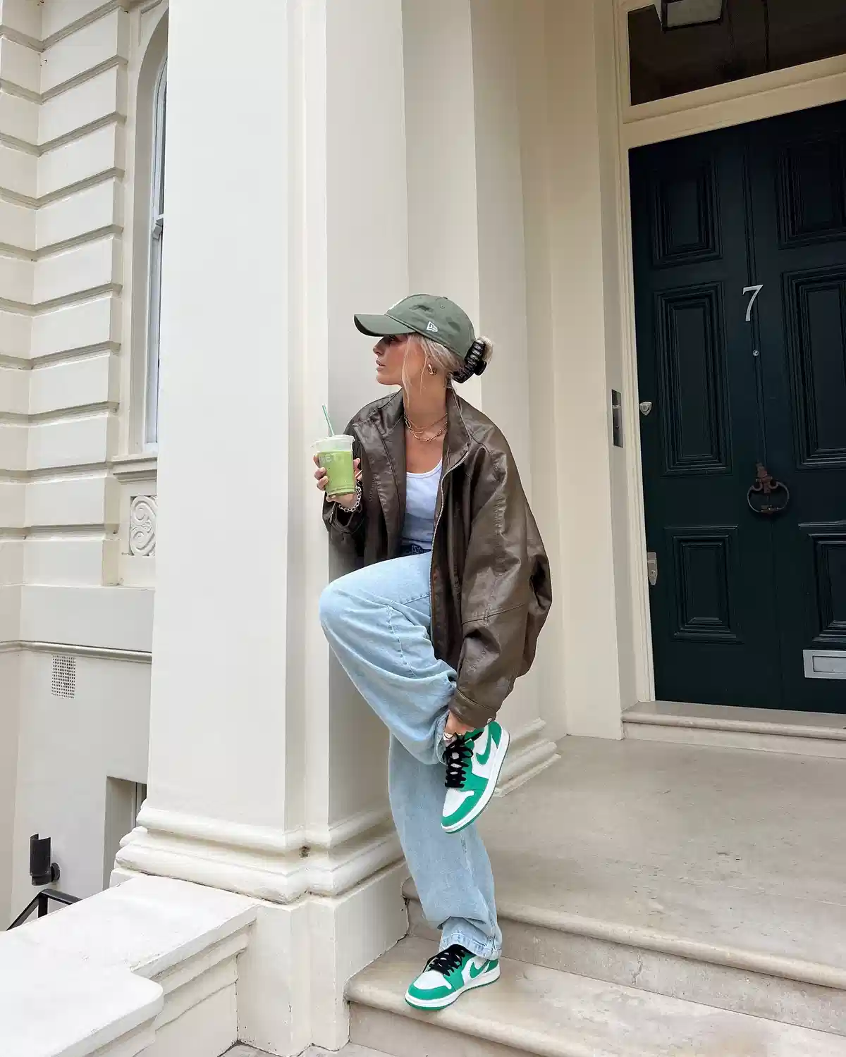 Green cap with oversized brown jacket and light-wash jeans