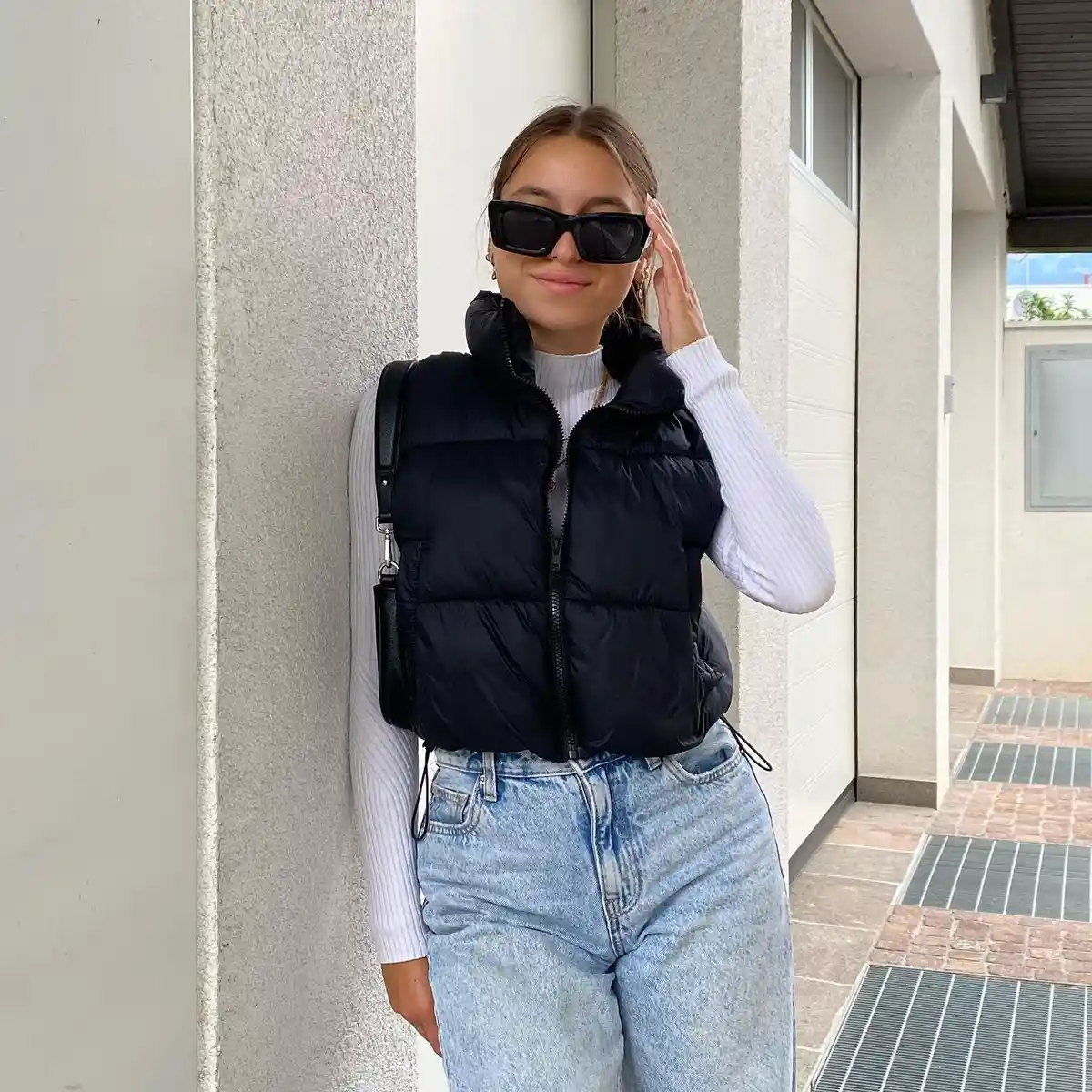 Black puffer vest over white ribbed top with light jeans