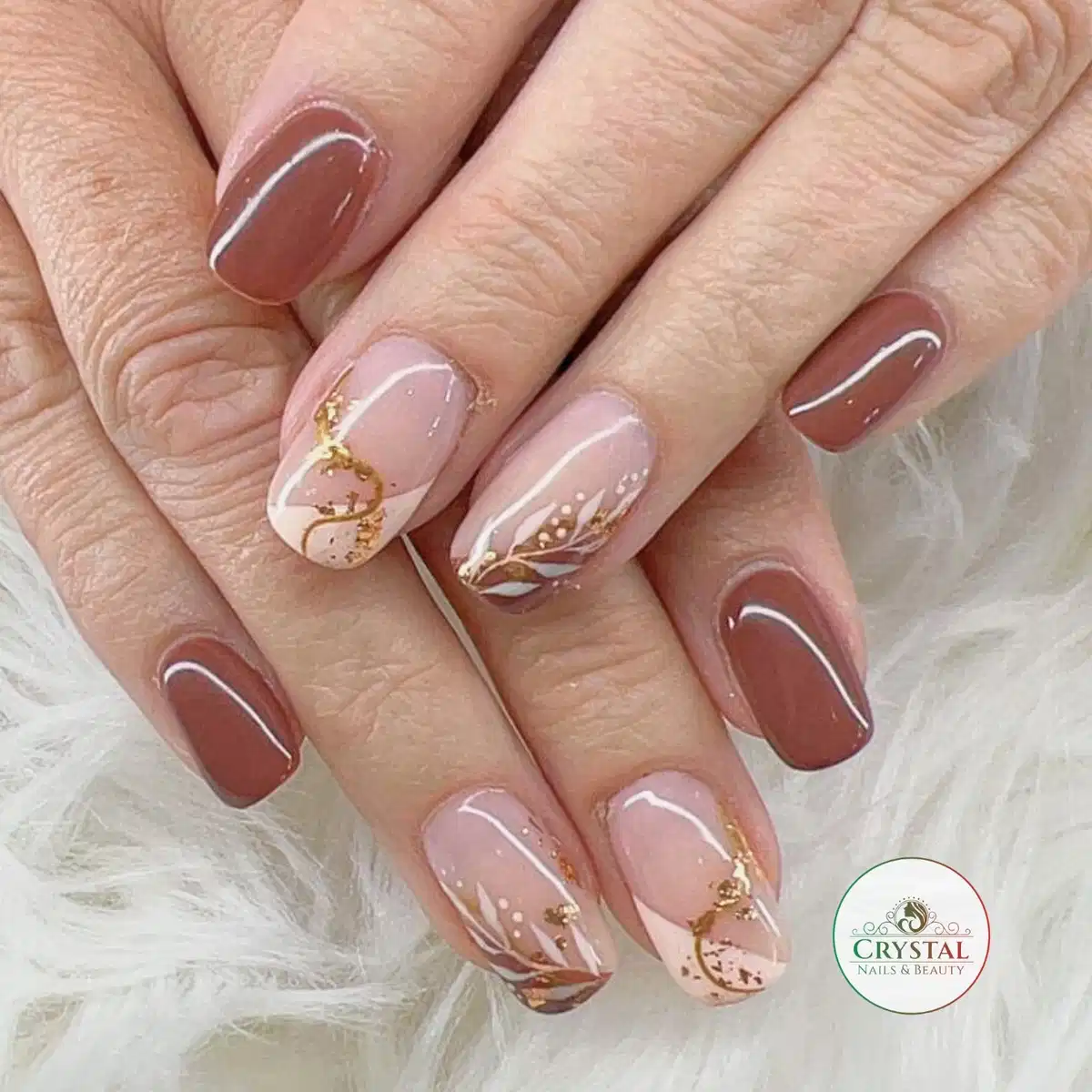 Brown and blush nails with gold flecks and delicate botanical line art