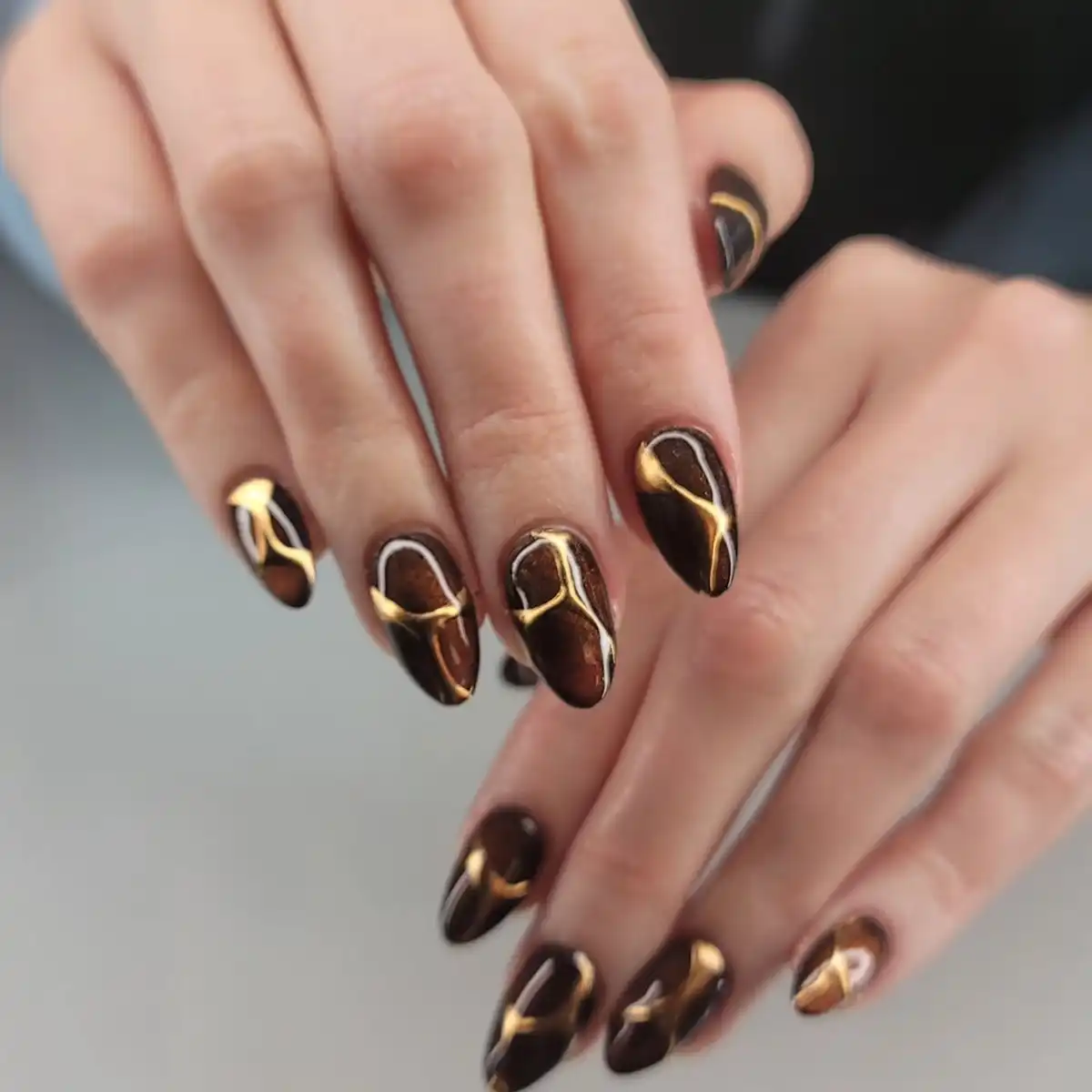 Dark chocolate nails with gold-and-white wavy line art