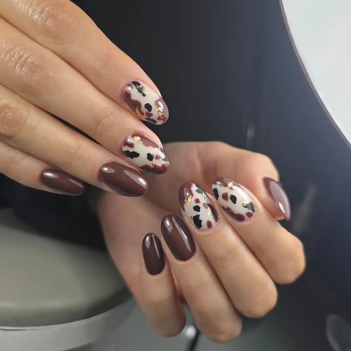 Deep brown manicure with spotted cream accent nails and gold flecks