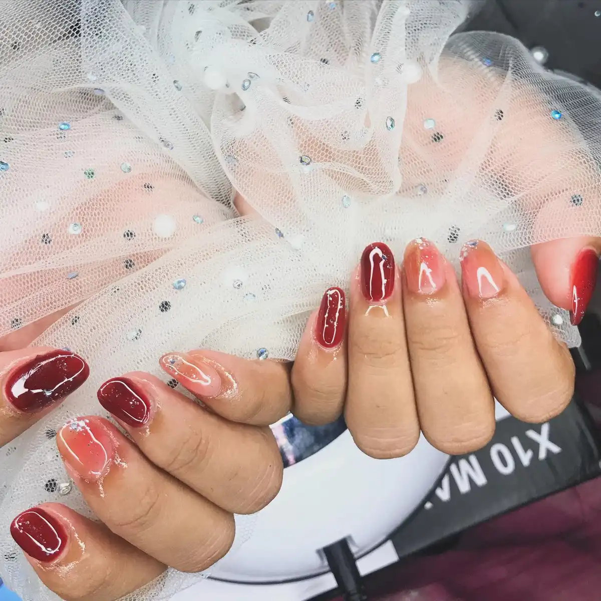 Maroon and Peach Glossy Nails with Subtle Glitter Accents
