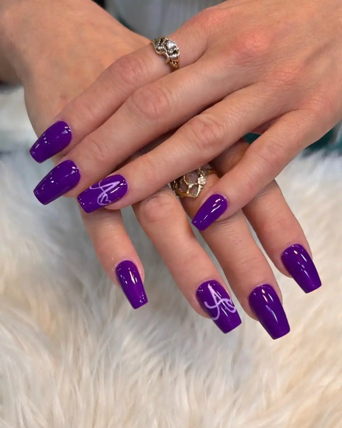 Bright purple square nails with white cursive line accents