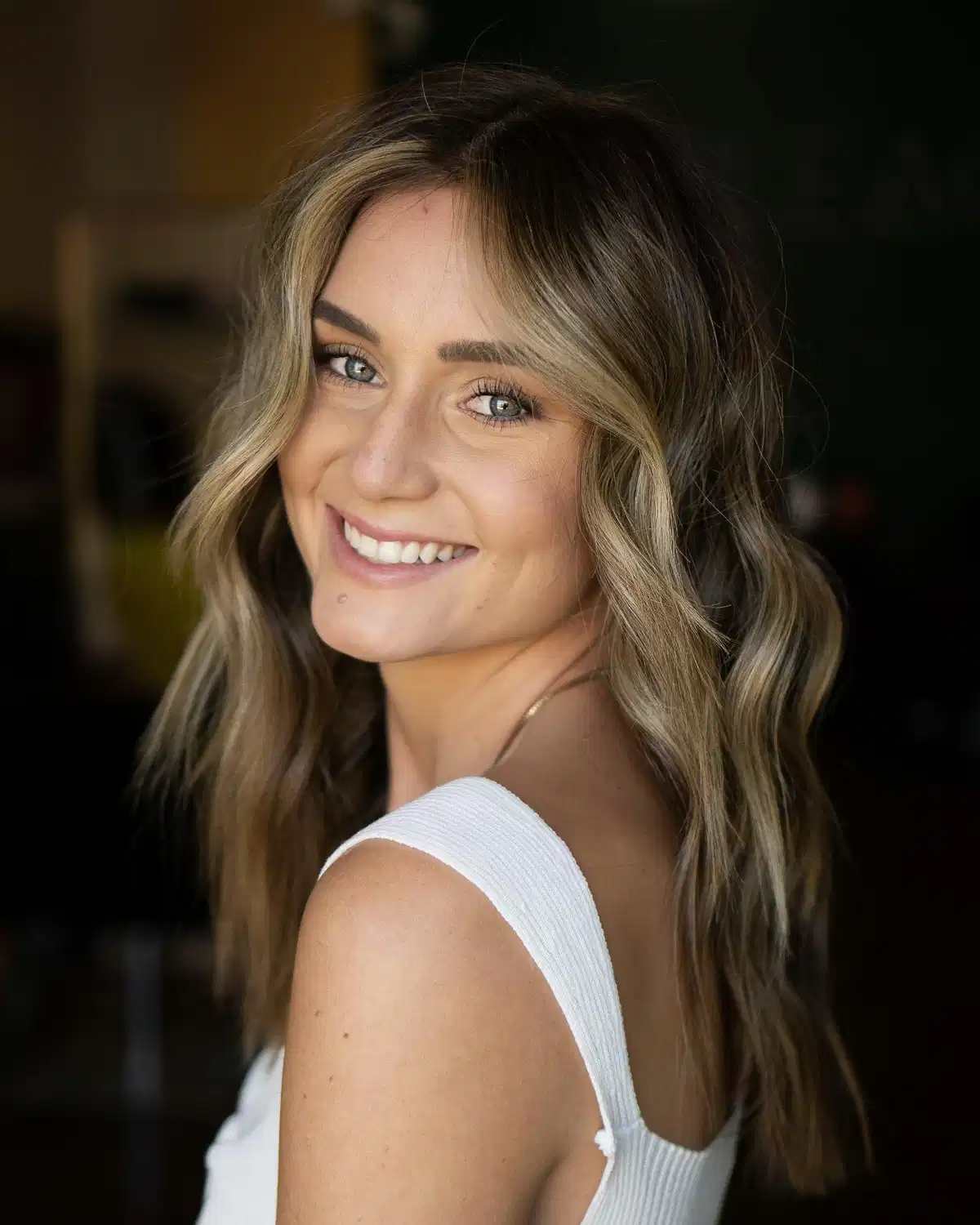 Wavy blonde with dark roots and face-framing highlights