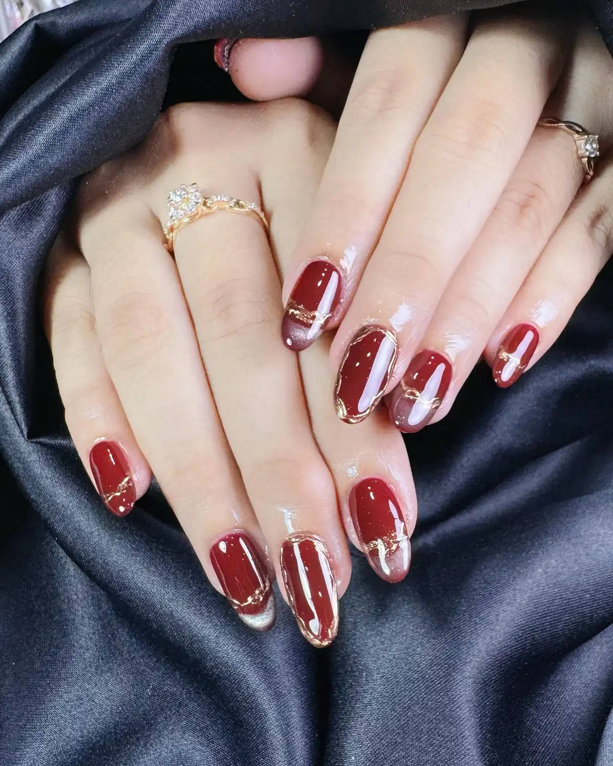 Glossy maroon nails with gold outlines and gray gradients