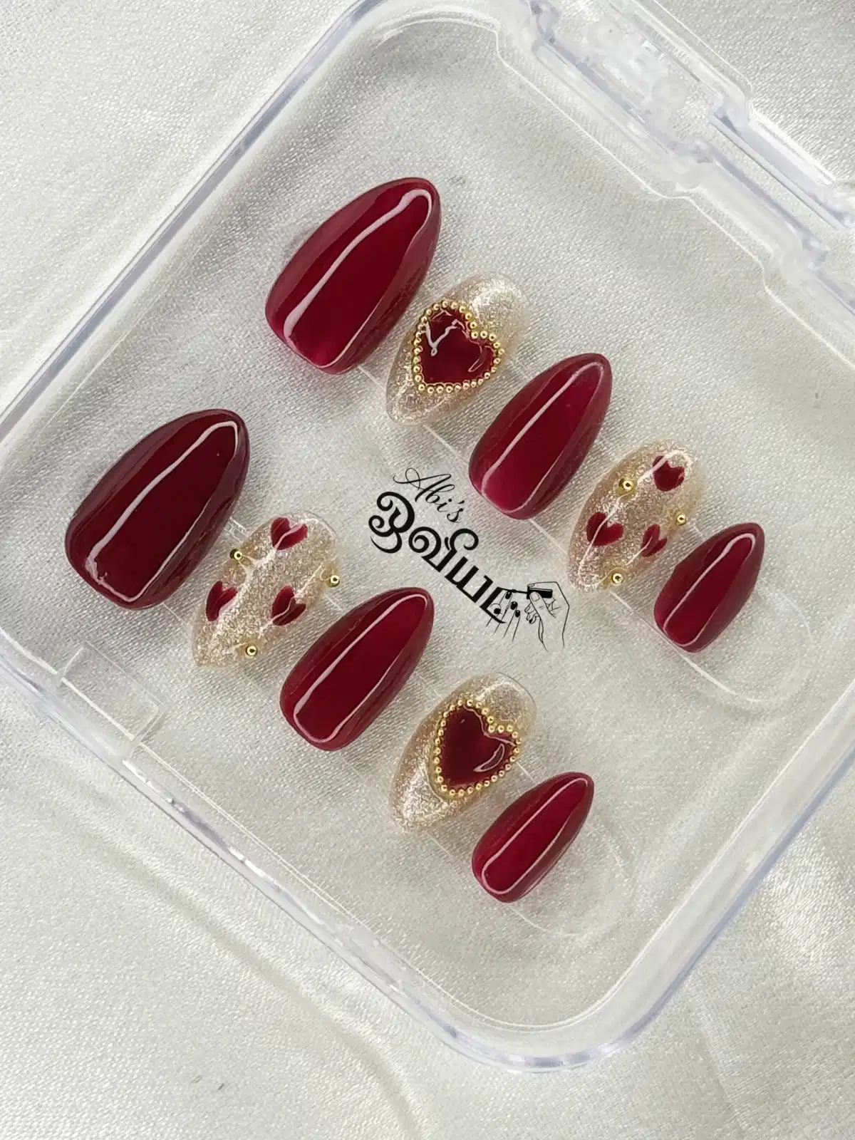 Maroon press-on set with clear glitter heart accents and gold studs