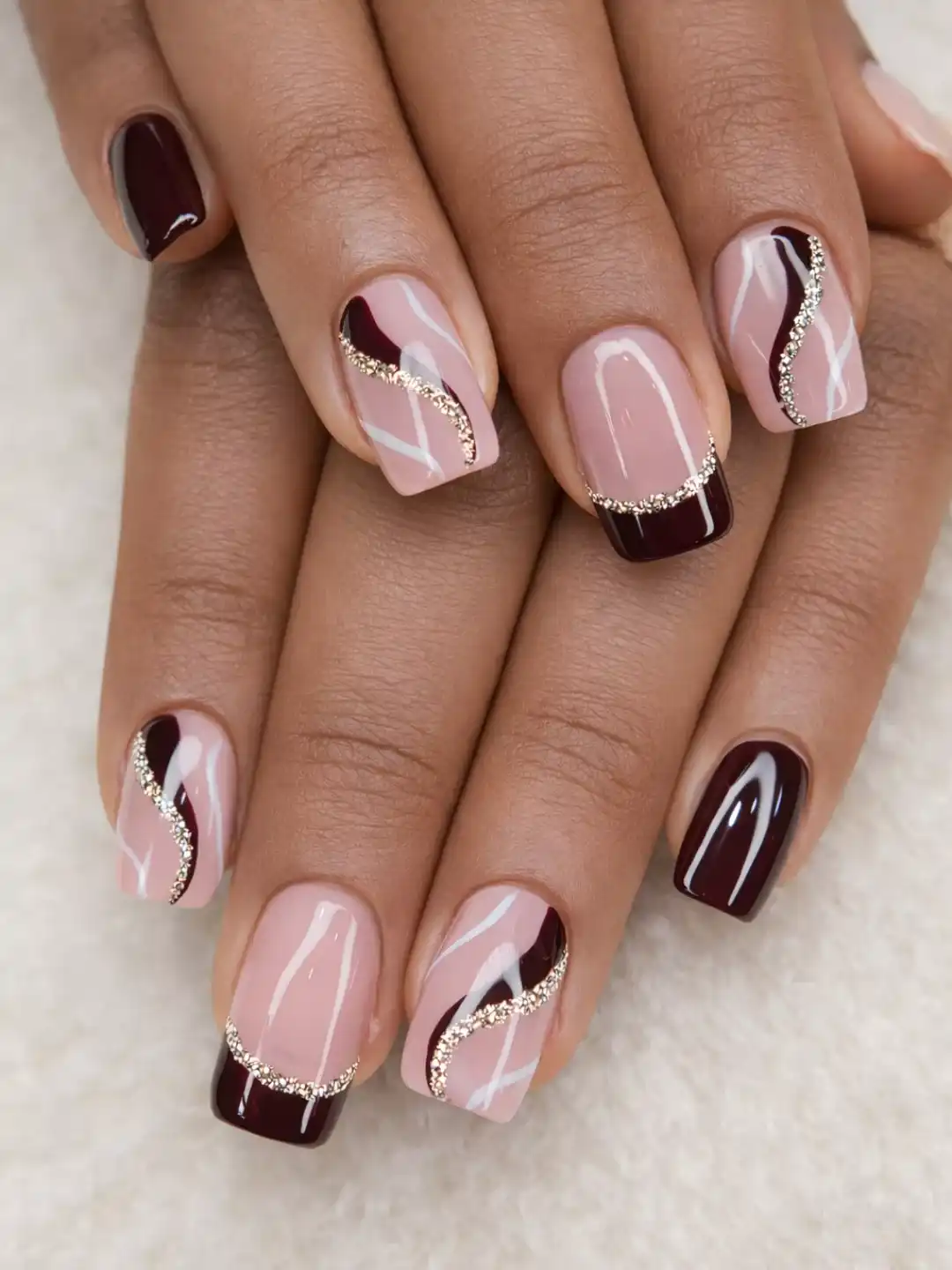 Pink-and-maroon glossy nails with curved rhinestone dividers