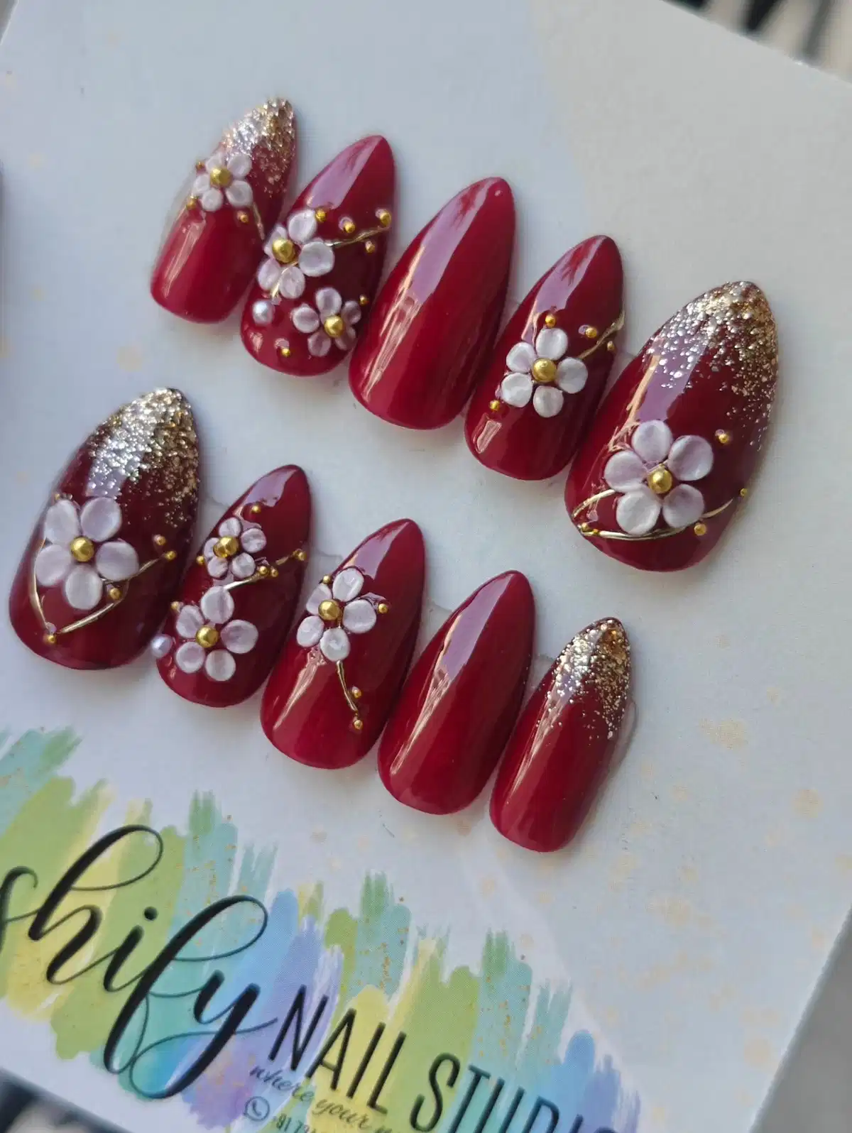 Maroon nail tips with white flowers and gold glitter tips