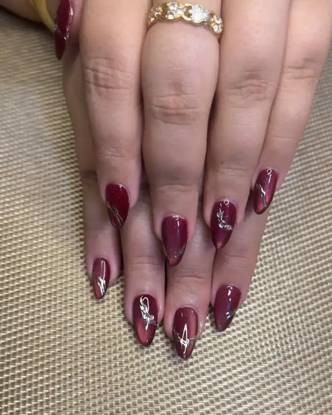Glossy maroon nails with subtle metallic tip accents