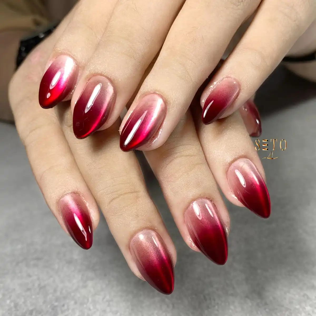 Glossy red ombrรฉ cat-eye style almond nails