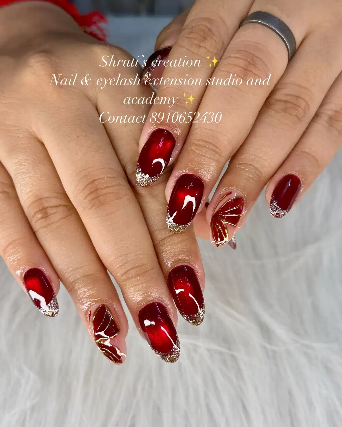 Deep red glossy nails with silver glitter tips and gold line accents