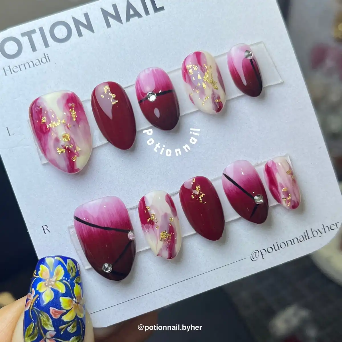 Maroon and pink marbled press-ons with gold foil and gem accents
