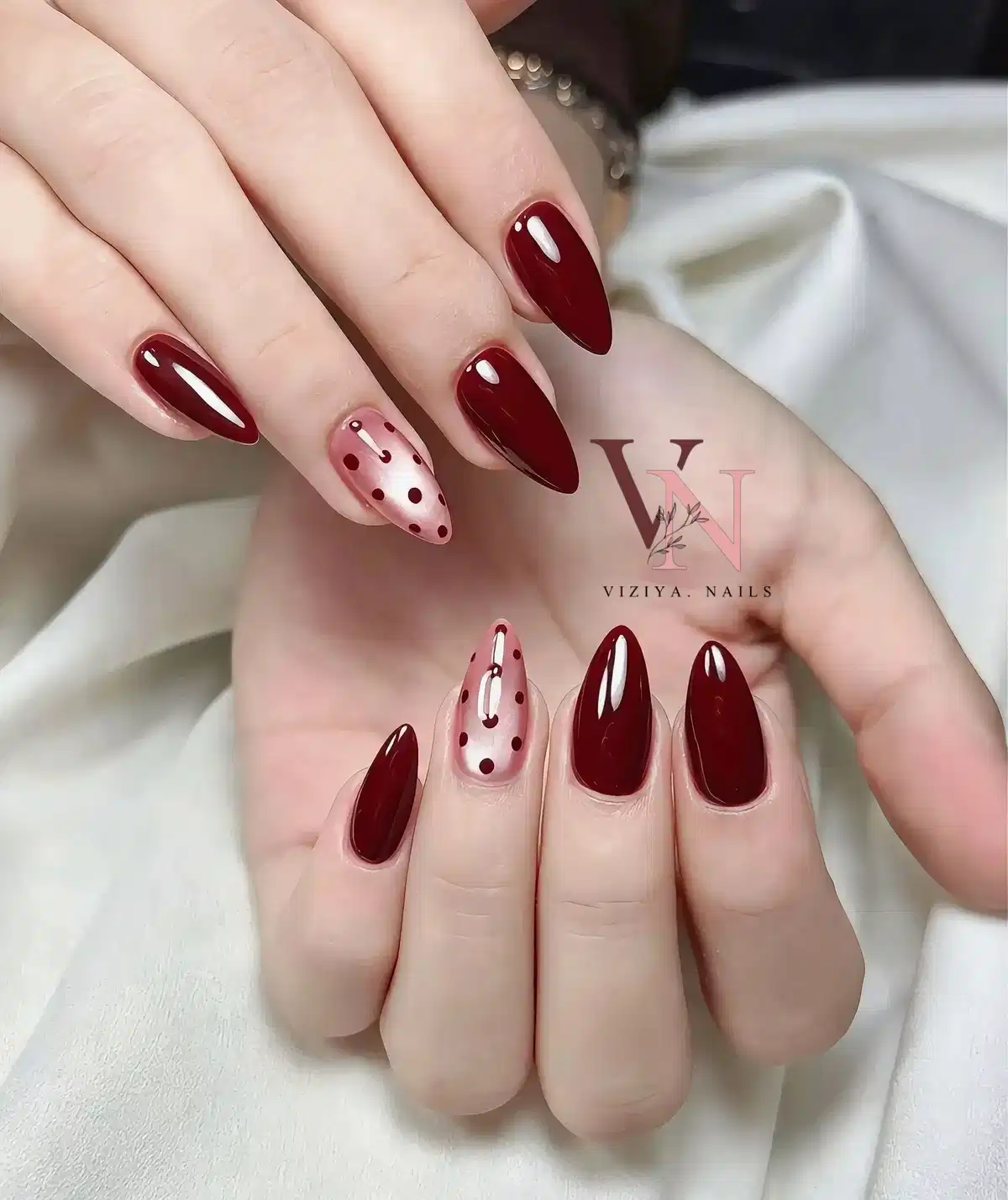 Deep burgundy stiletto nails with sheer polka-dot accents