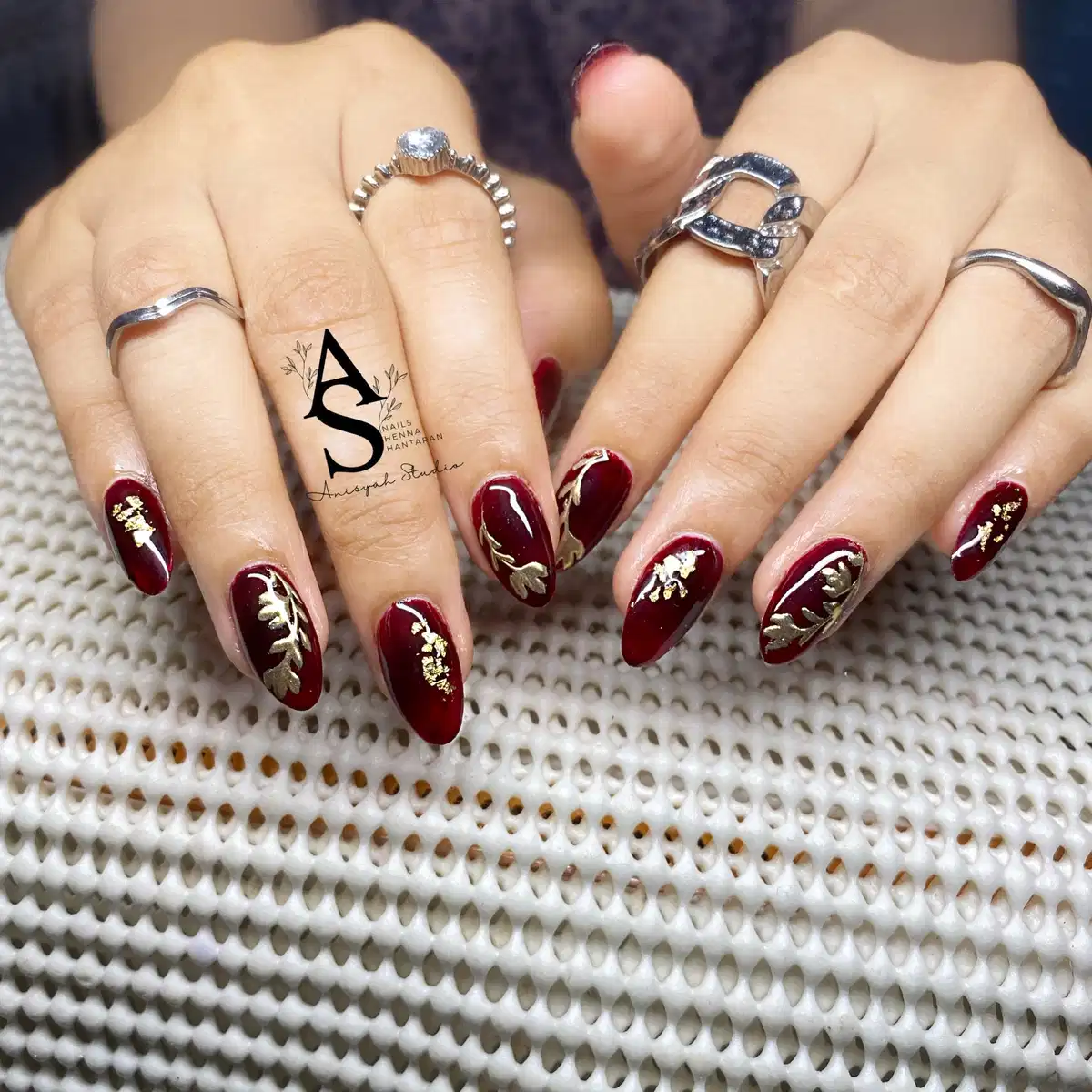 Maroon nails with gold leaf and botanical motifs
