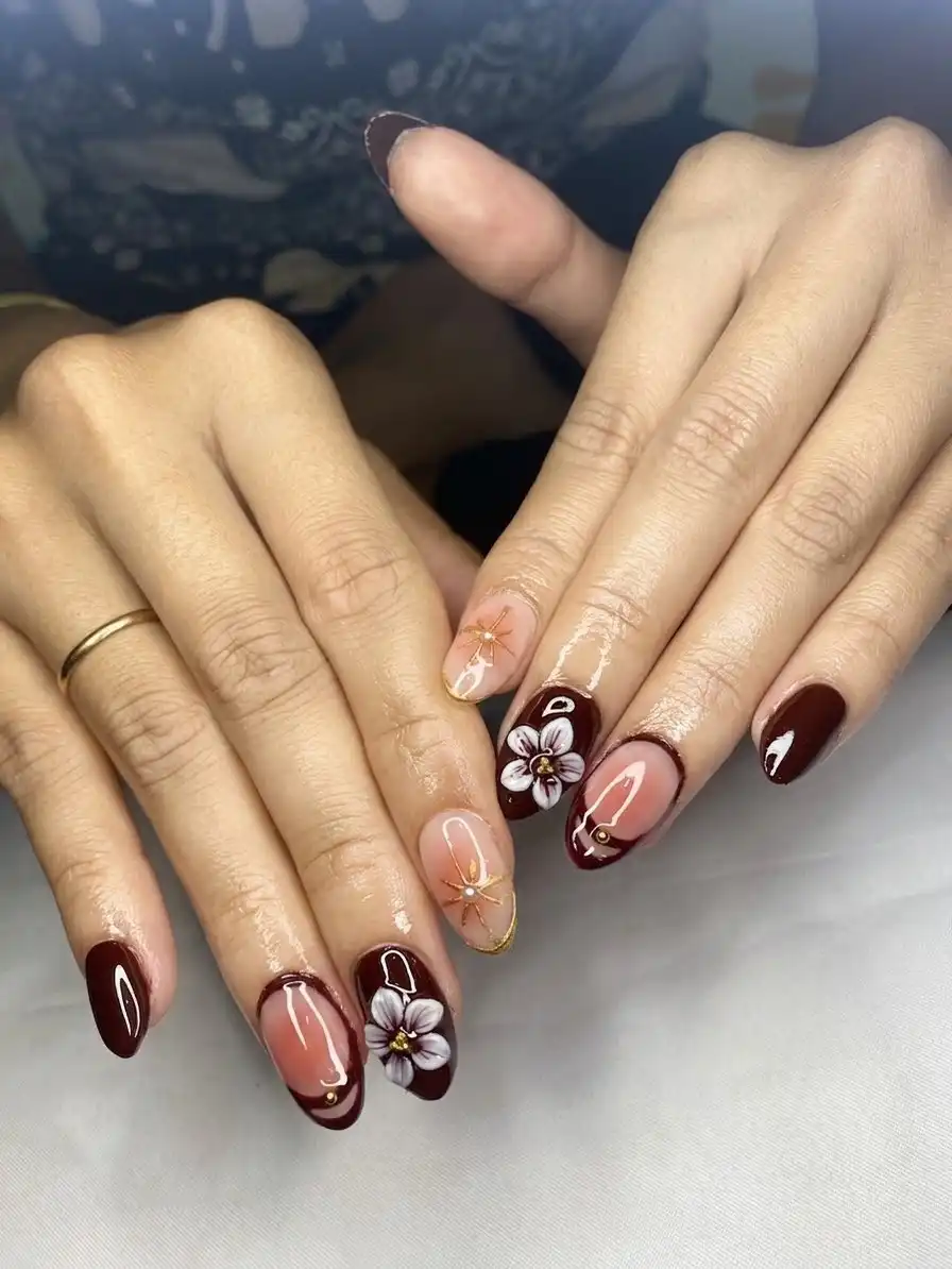 Maroon and nude nails with large white floral art and gold lines