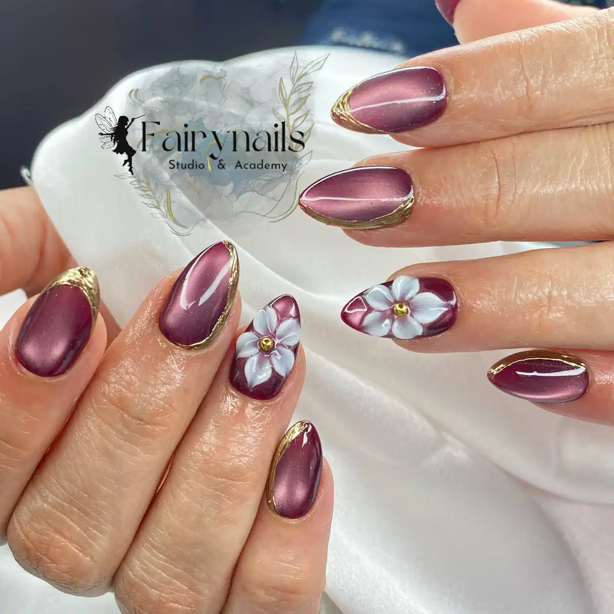 Mauve-maroon glossy nails with gold edging and 3D white flowers
