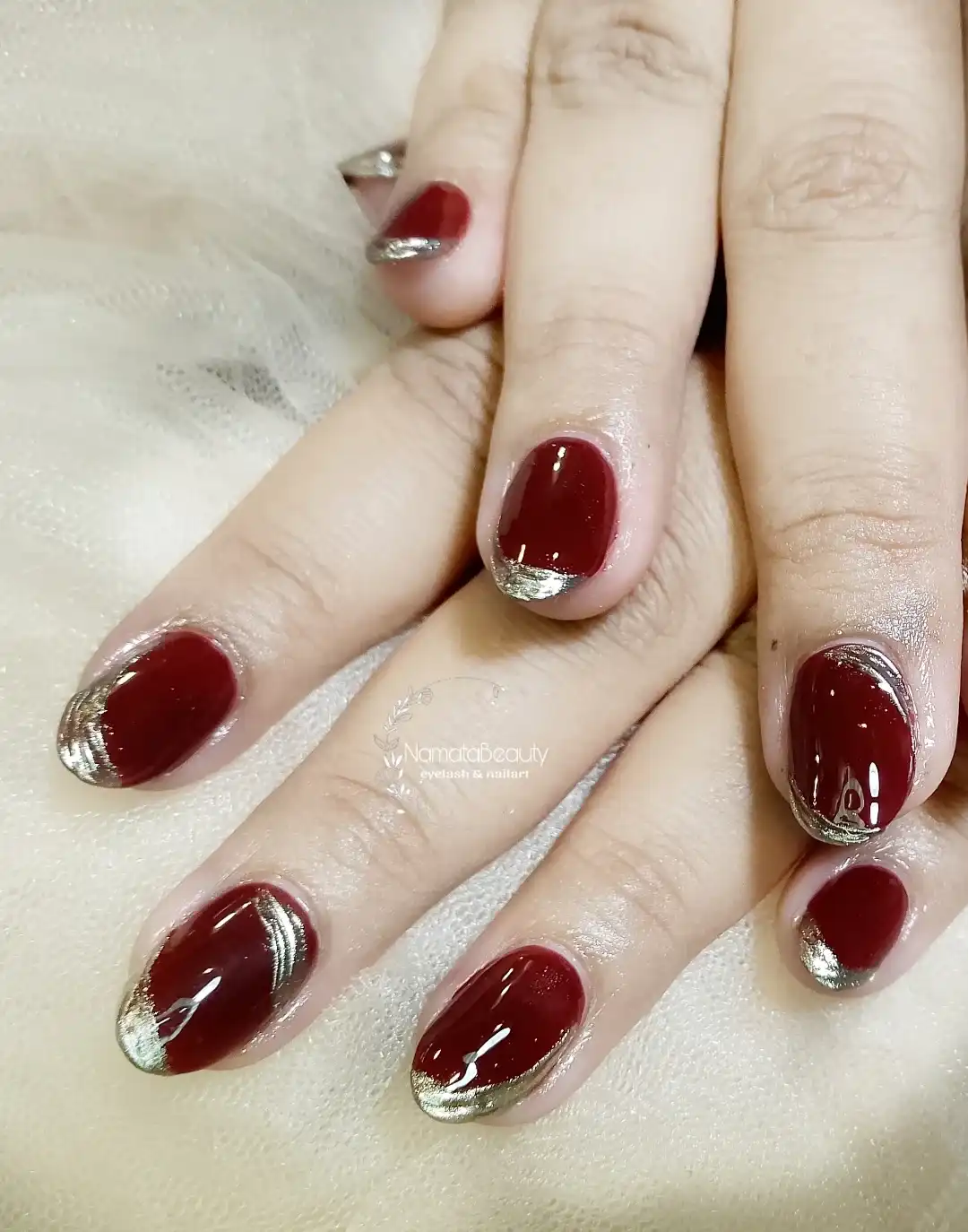 Glossy maroon short nails with metallic silver French tips