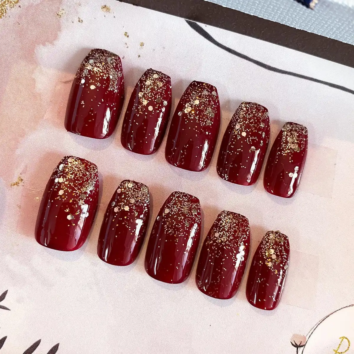 Maroon glossy set with gold glitter concentrated at the cuticle