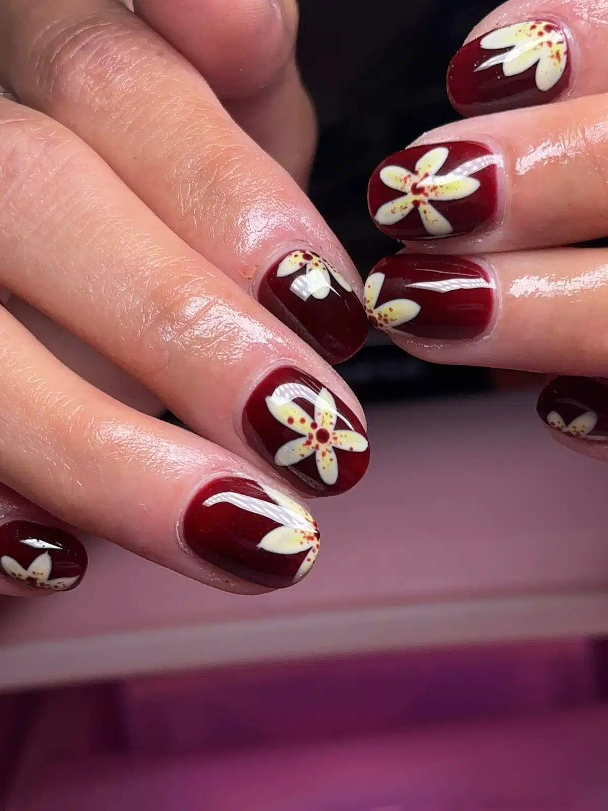 Glossy maroon short nails with white floral art