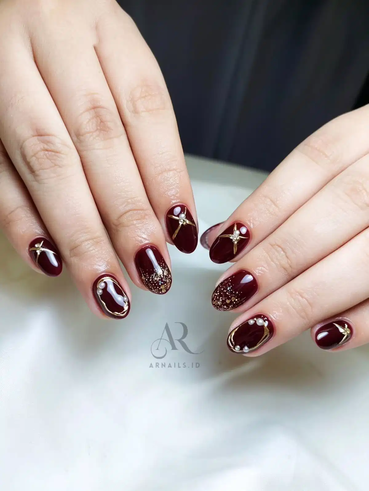 Deep maroon with gold frames, pearl-like beads, and glitter tips