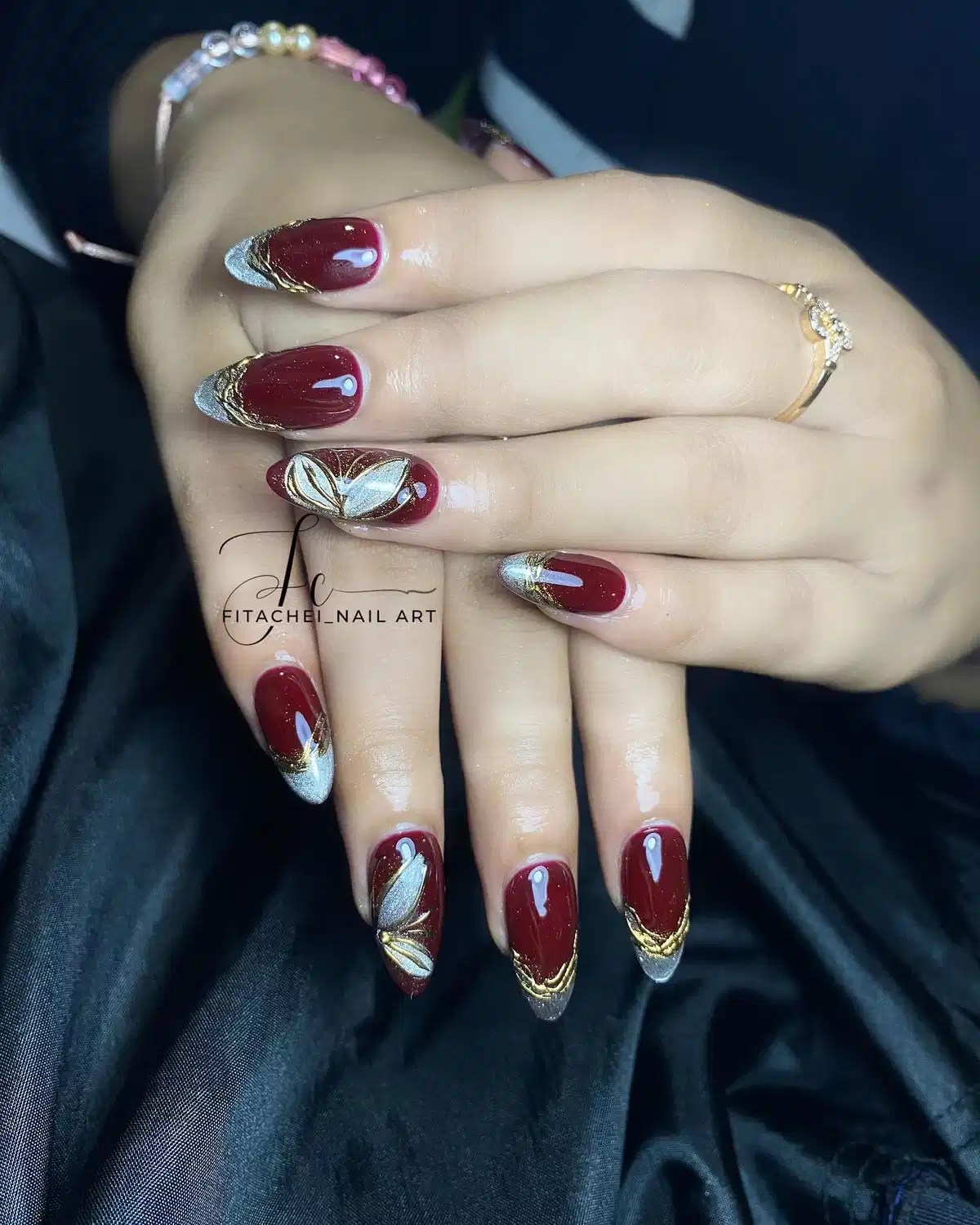 Maroon almond nails with silver-glitter tips and white-gold leaf motifs