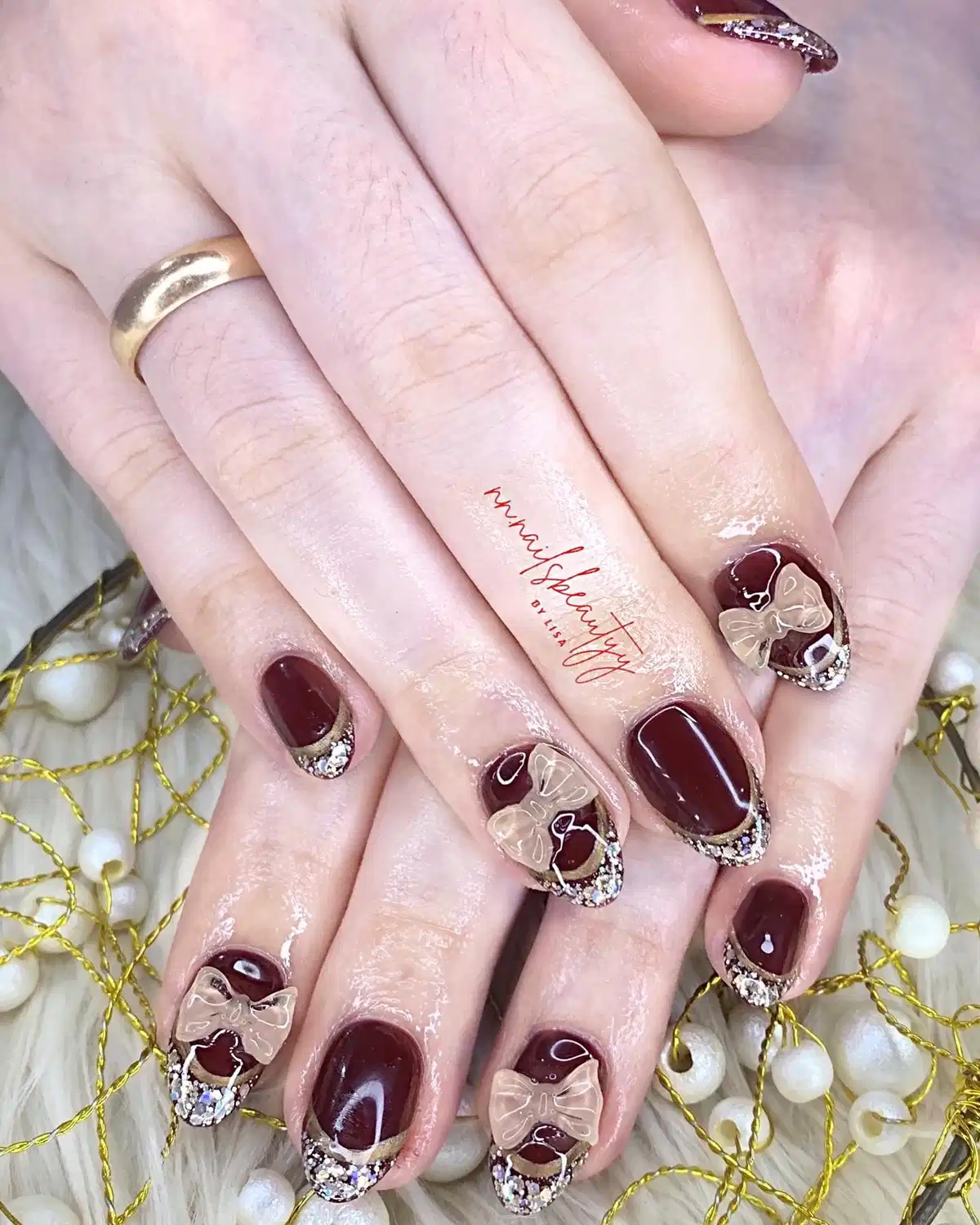 Maroon nails with 3D bows and rhinestone-glitter tips