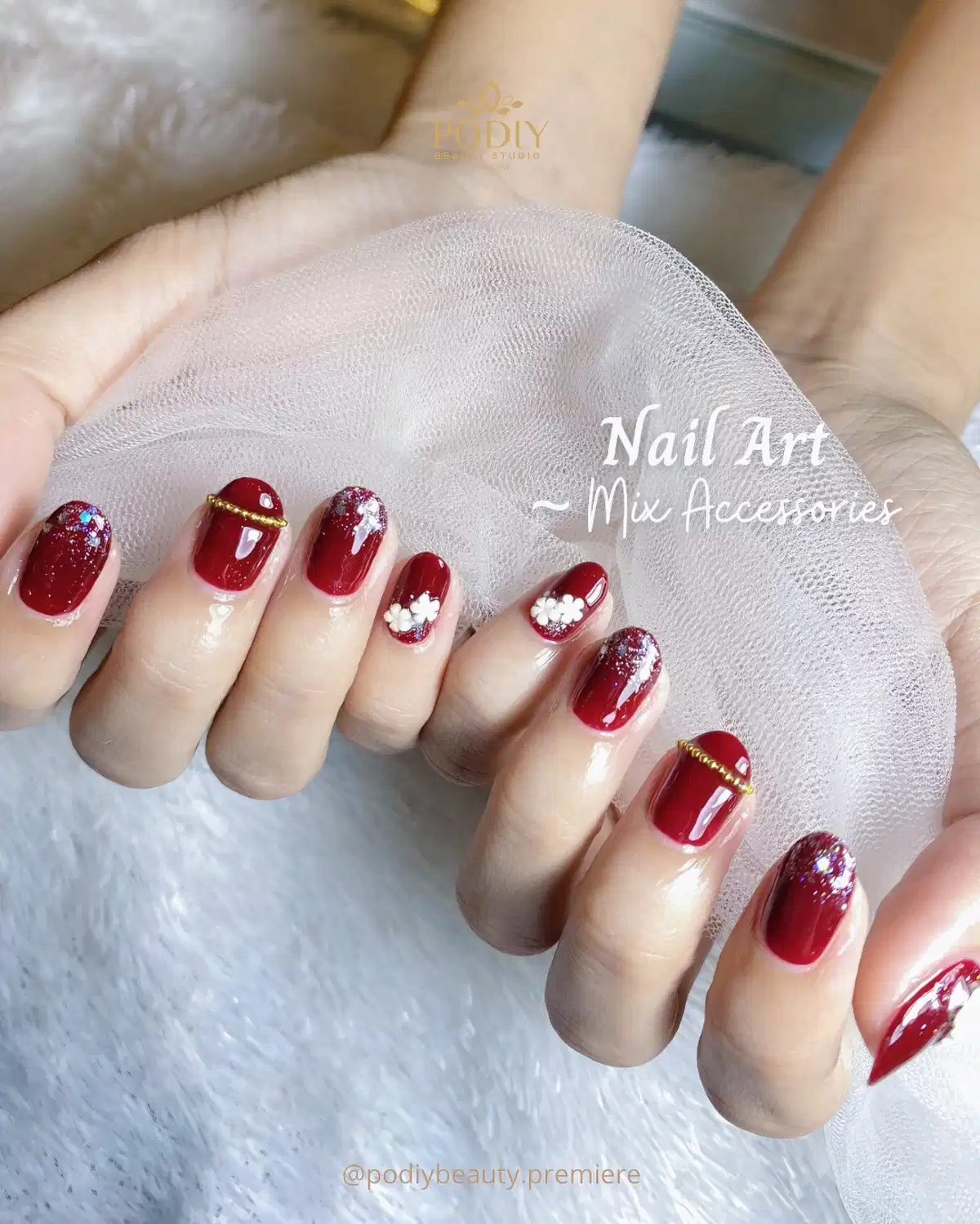 Glossy maroon with glitter tips, white flowers, and gold band accents