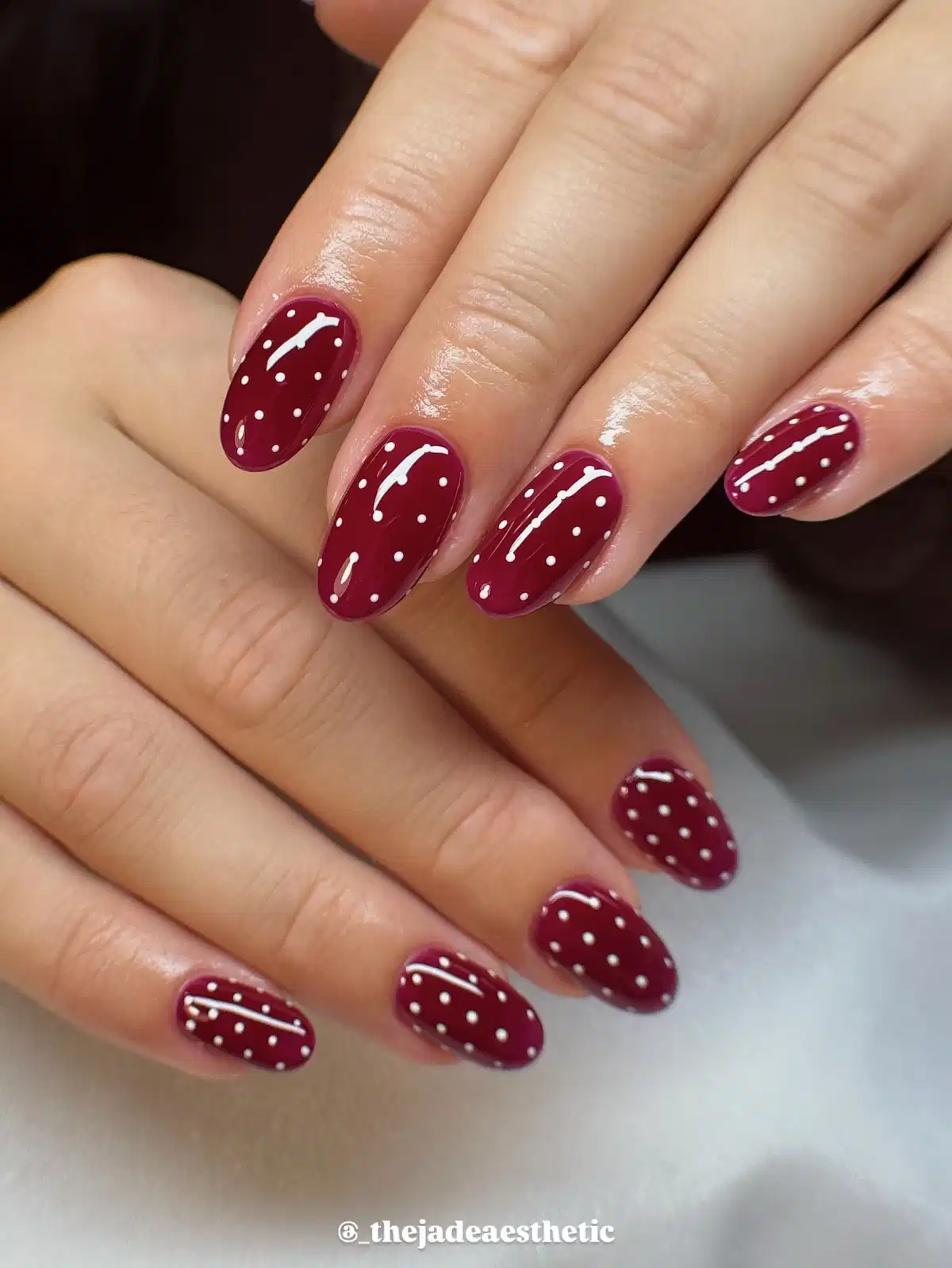 All-over maroon nails with fine white polka dots