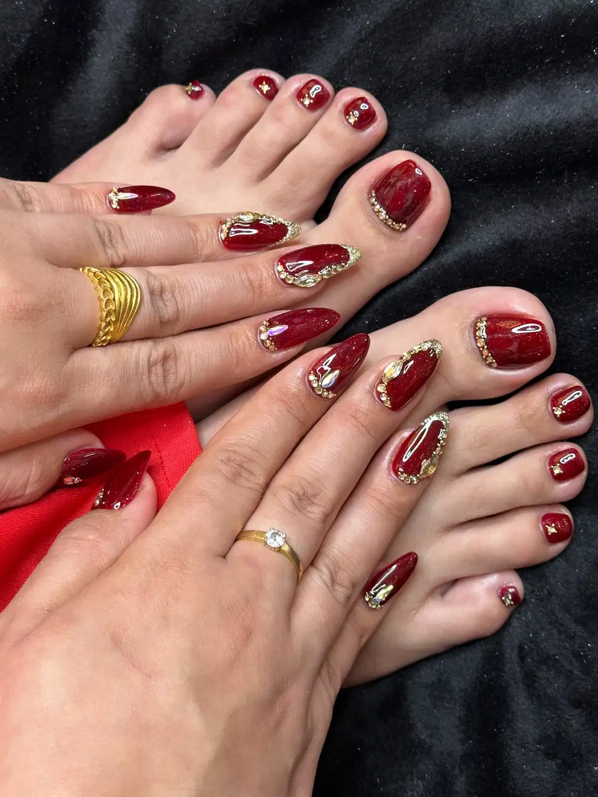 Matching maroon manicure and pedicure with gold edging and rhinestones