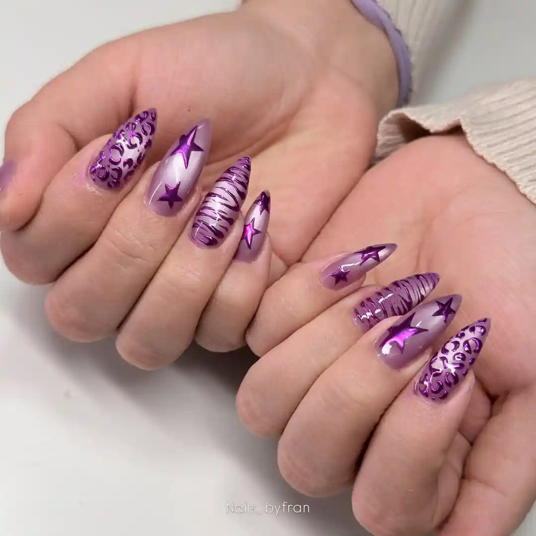 Translucent nude stiletto nails with purple stars, stripes, and ornamental swirls