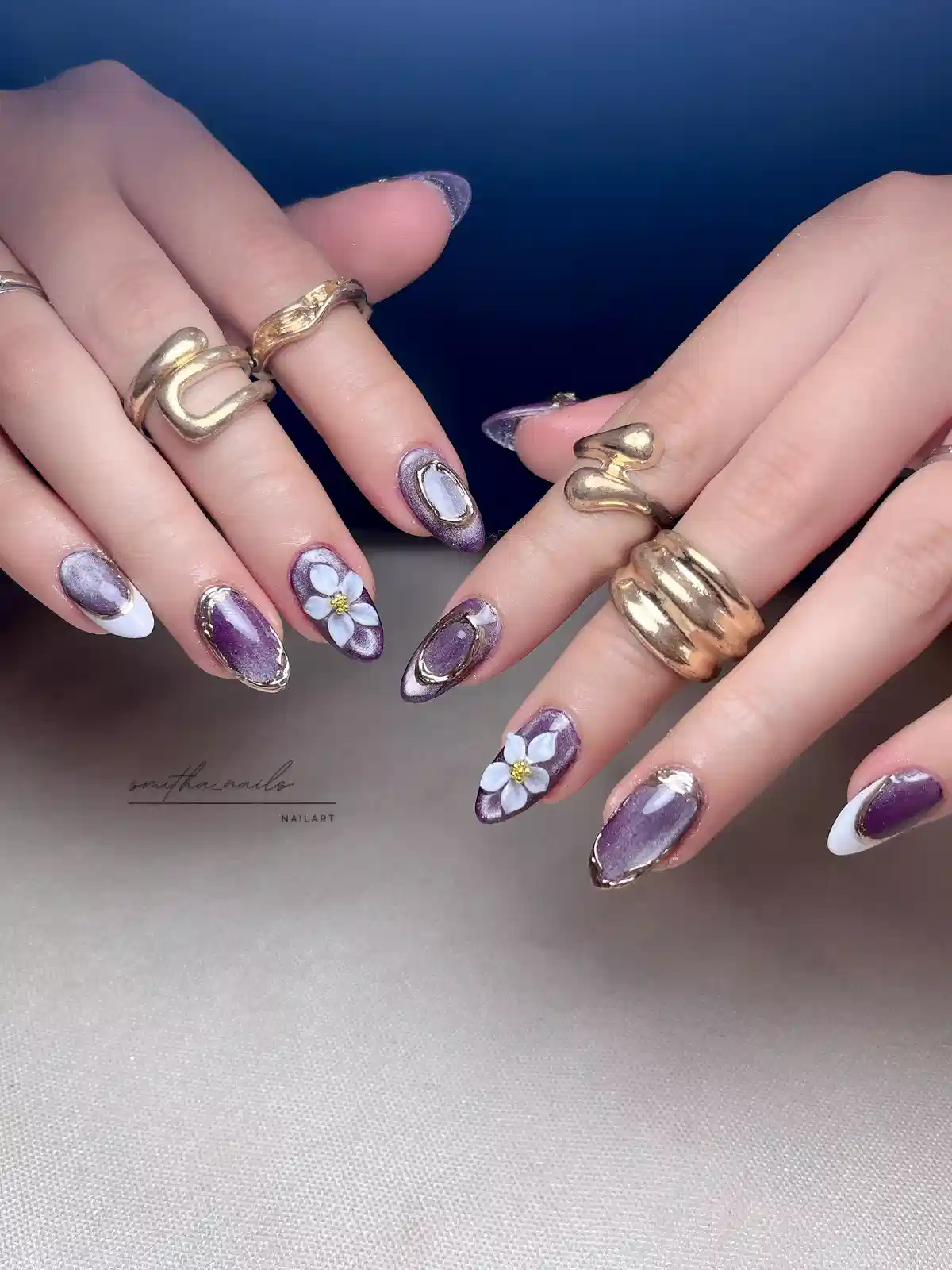 Purple metallic almond nails with white French tips, oval frames, and 3D flowers