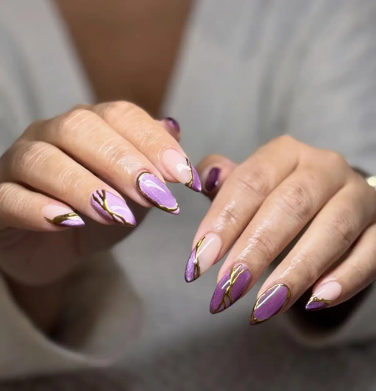 Nude and purple almond nails with gold branching lines