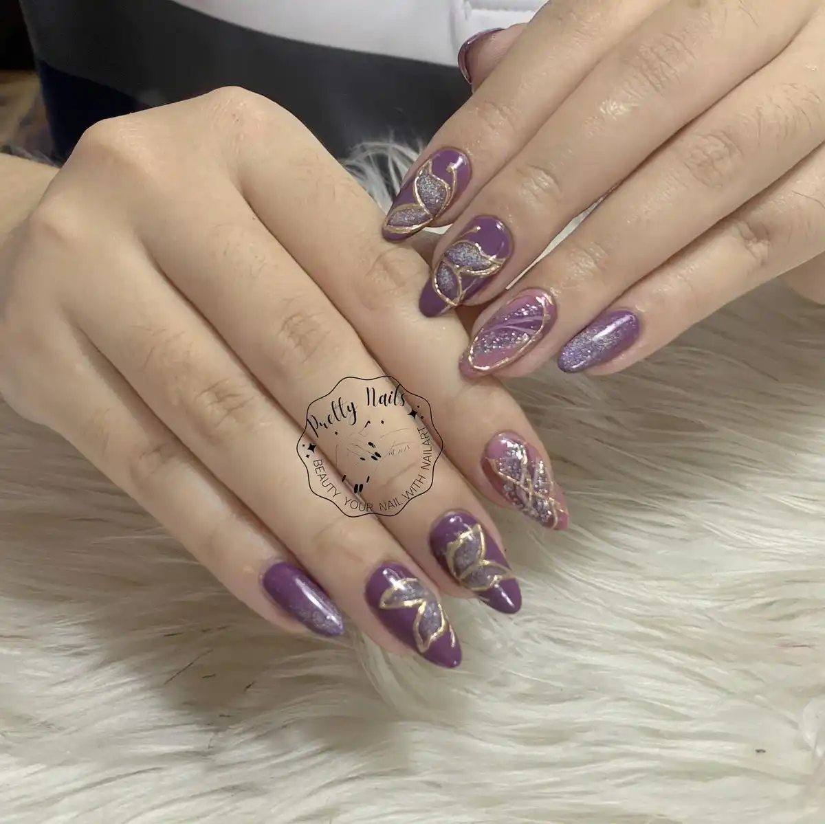 Purple almond nails with gold outlines and glitter panels