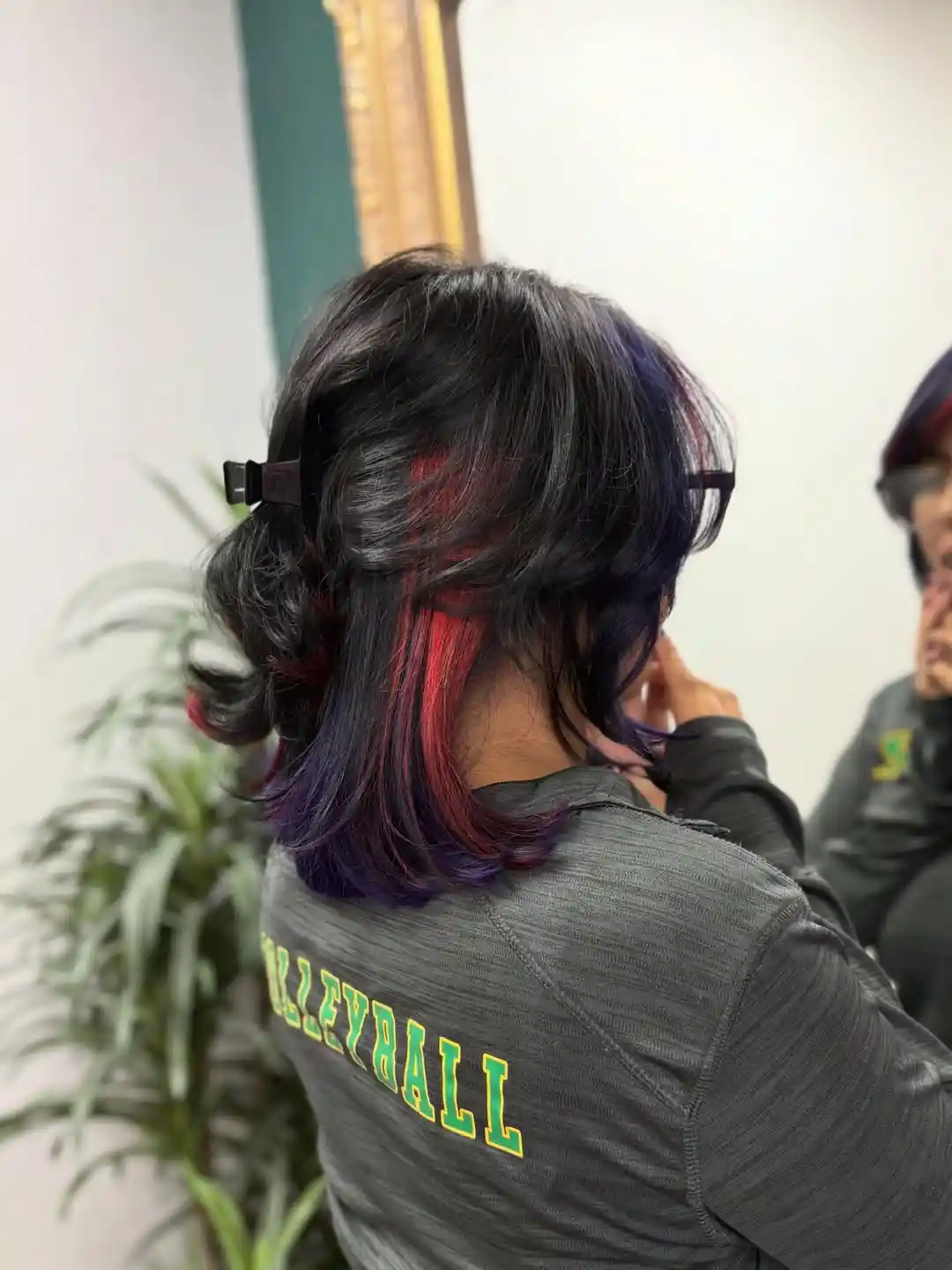 Clipped-back short hair with red/purple streaks