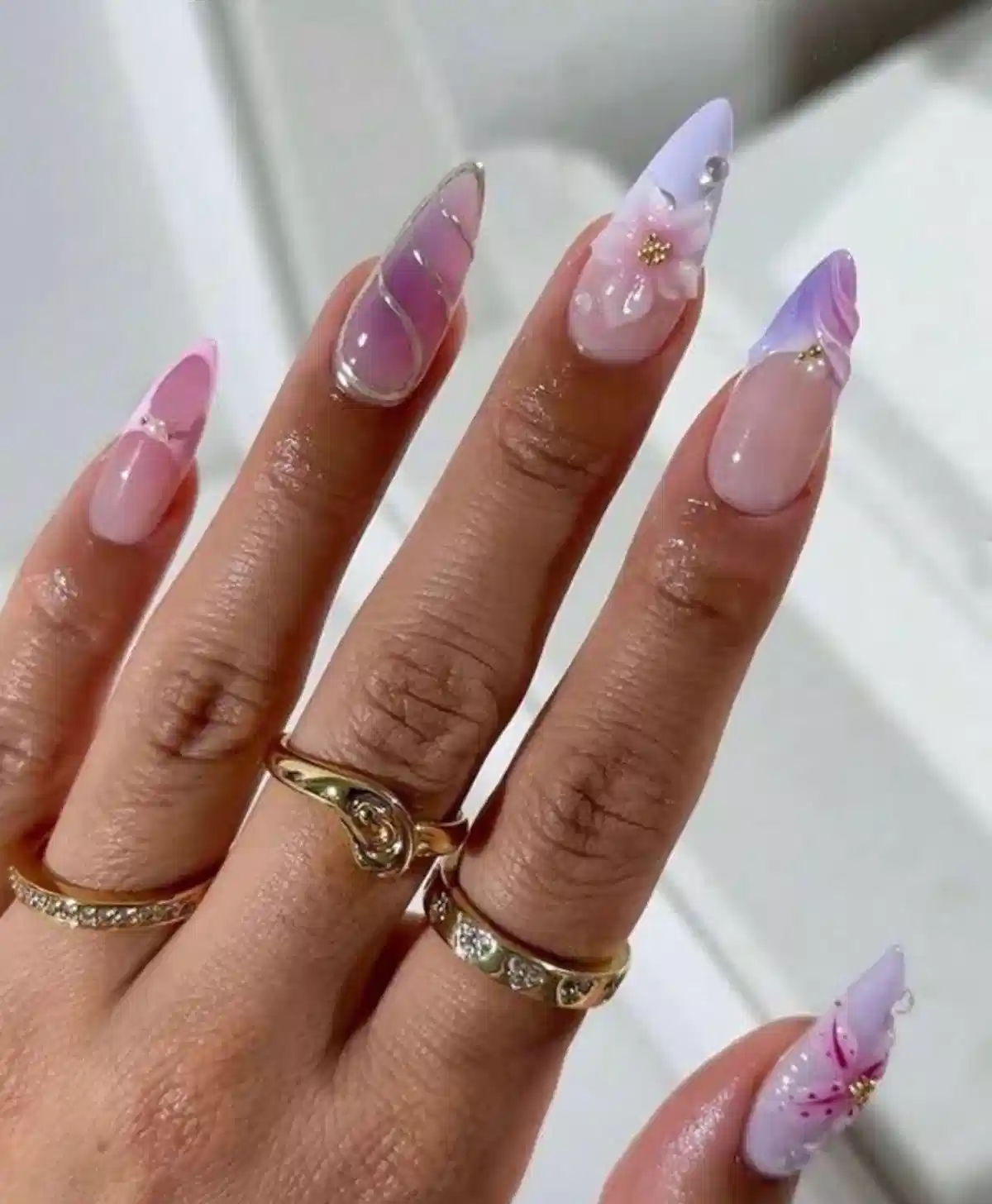 Pink-to-purple stiletto nails with floral accent and glossy overlays