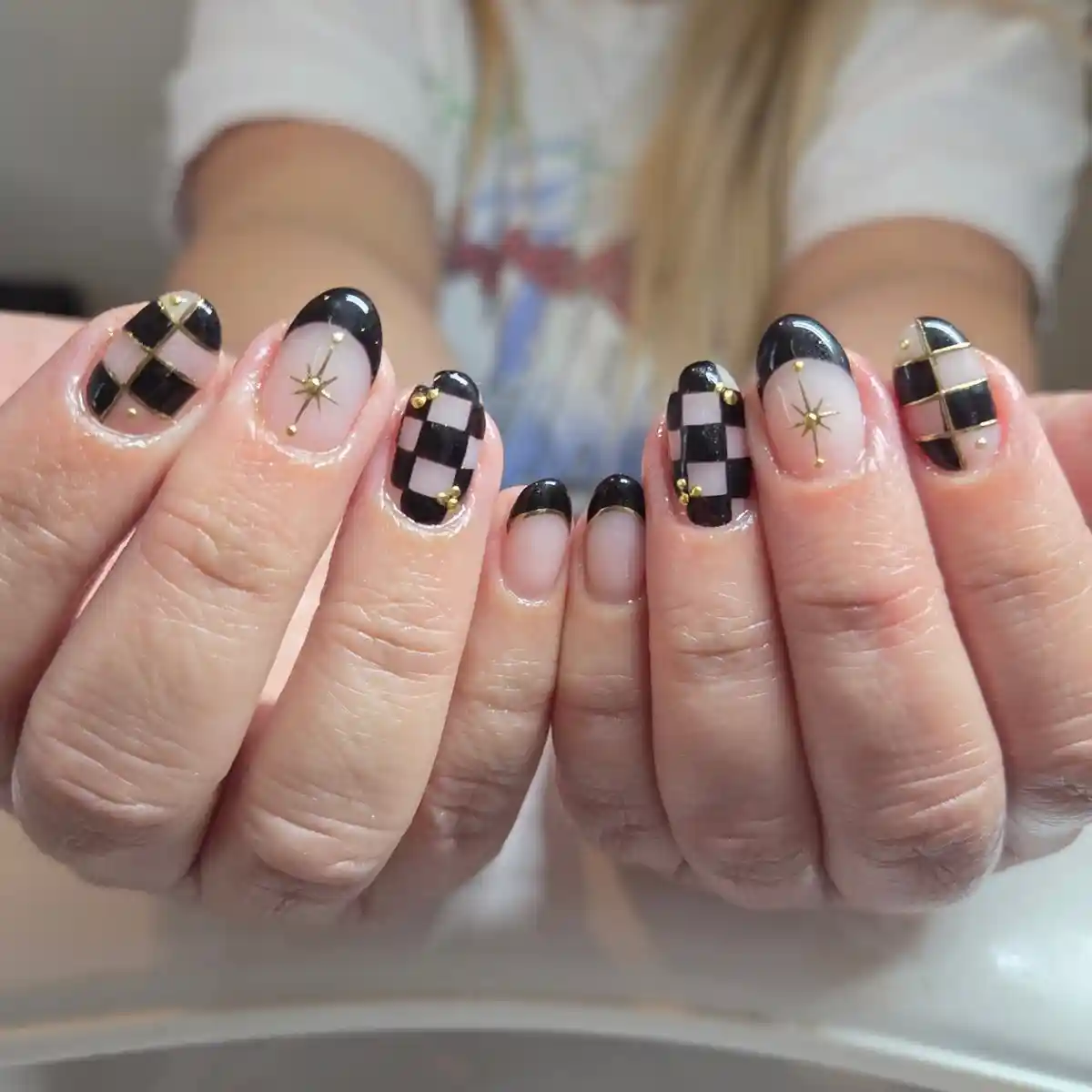 Short checkerboard nails with gold lines and studs