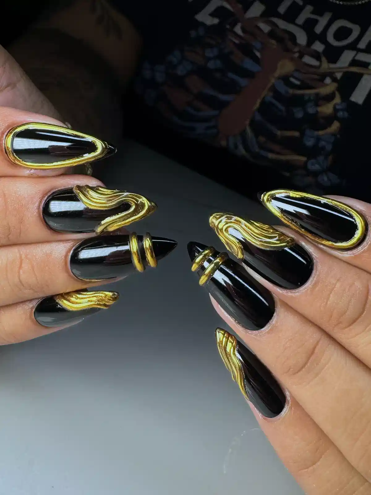 Glossy black nails with bold raised gold accents