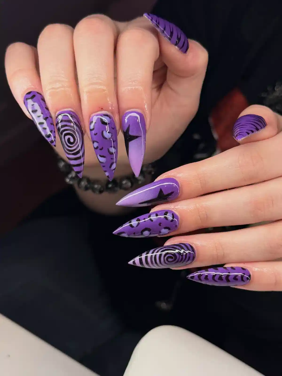 Long purple stilettos with black spirals, stars, and spots