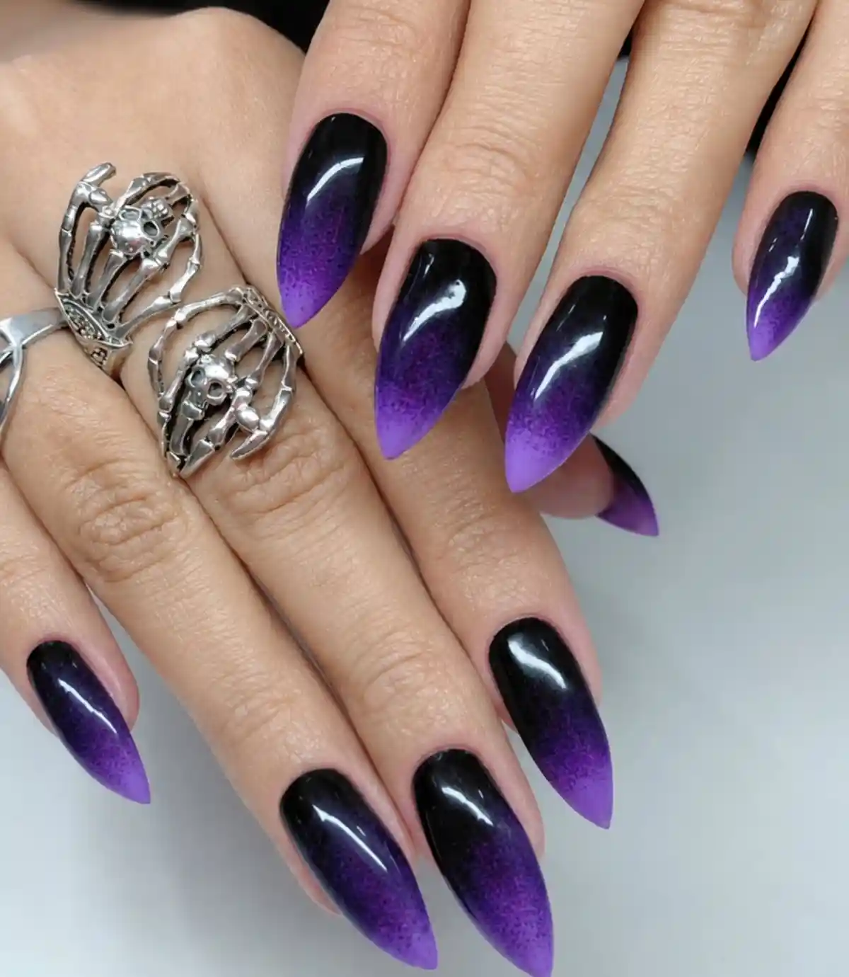 Black-to-purple ombré almond nails with speckled purple tips